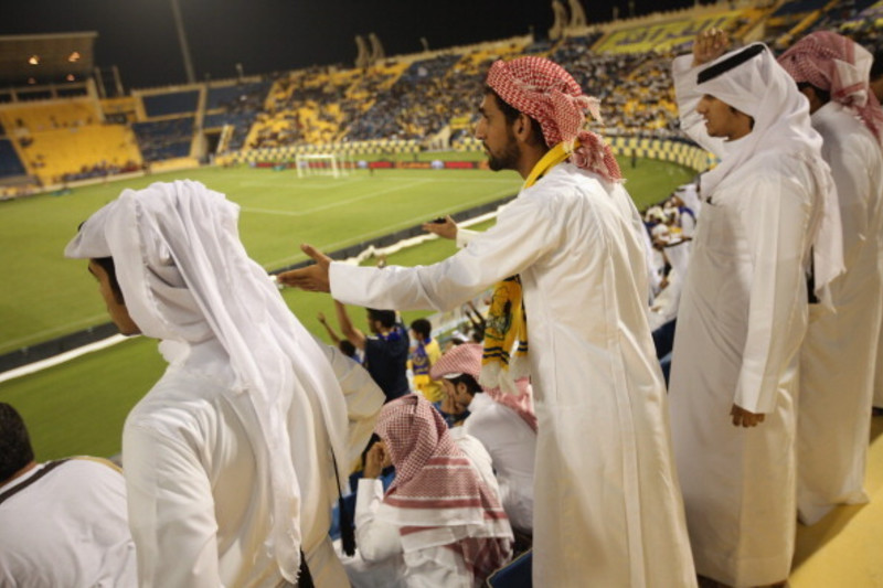 Fans wearing traditional local dress react to play