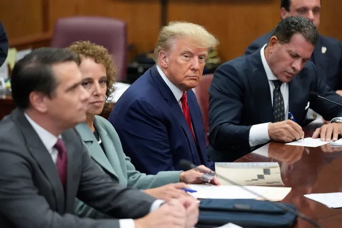 Former president Donald Trump sits at the defense table with his legal team